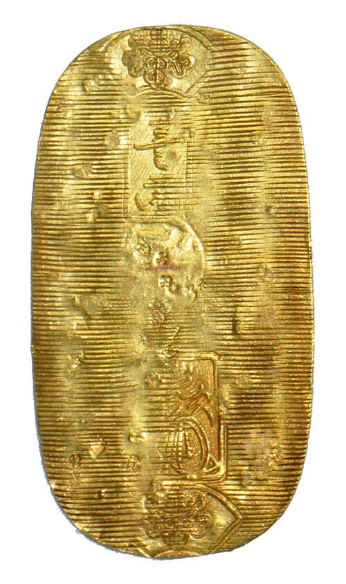 Round gold-colored coin with engraved beckoning cat raising left paw, red ribbon attached