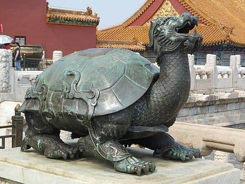Gold resin Dragon Turtle figurine with dragon head, turtle shell on coin bed, and baby turtle on its back