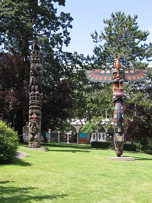 A small hand-carved cedar totem pole featuring Eagle and Bear figures in Pacific Northwest formline style