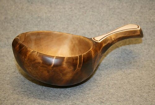 A hand-carved Finnish kuksa cup made from birch burl wood, showing natural grain patterns