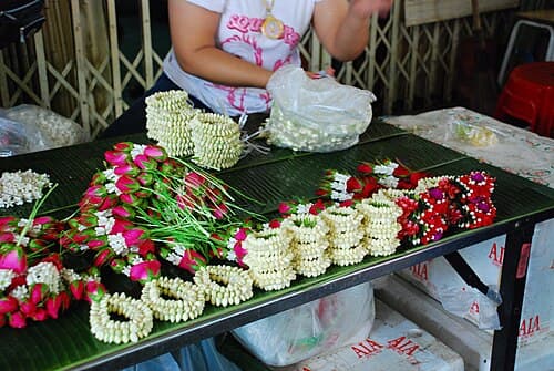 Intricate Thai phuang malai garland of white jasmine and orange marigolds on temple offering tray