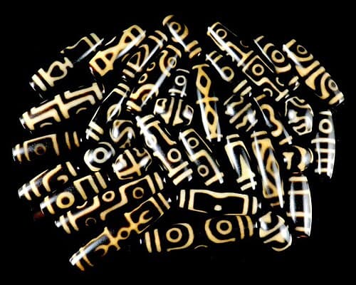 Ancient Dzi bead with nine eye-like circular patterns on striped agate on red cord